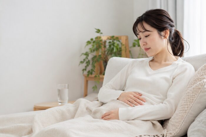 自宅でお腹を押さえて休んでいる画像